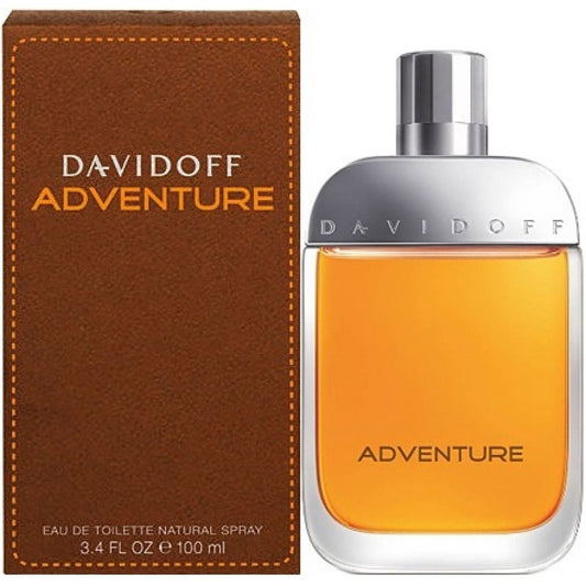 A bottle and box of ADVENTURE DAVIDOFF 3.4 EDT SP FOR MEN feature an orange liquid with a silver cap embossed with DAVIDOFF. The brown box showcases bold orange lettering for the brand and product name.